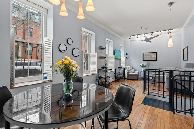 dining area with light wood-type flooring, track lighting, and ornamental molding