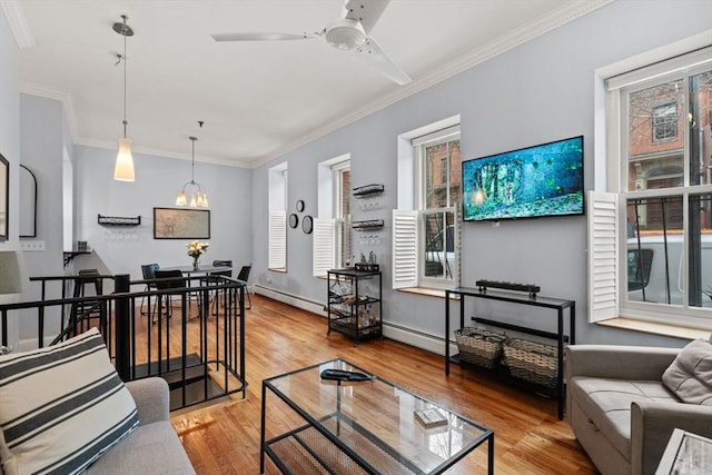 living room featuring hardwood / wood-style flooring, a baseboard heating unit, ornamental molding, and ceiling fan with notable chandelier