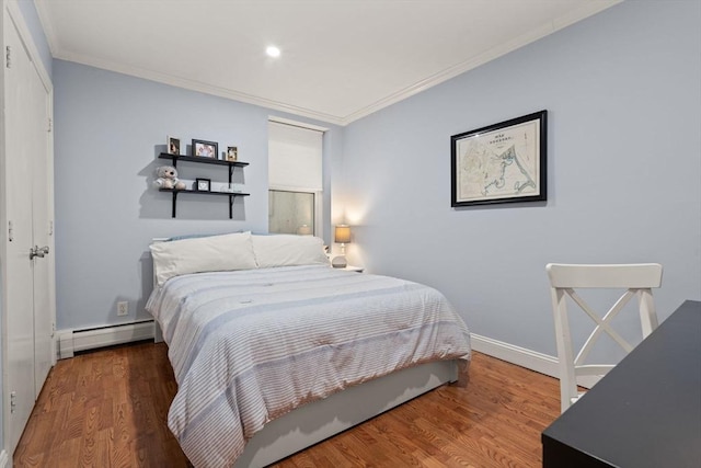 bedroom with crown molding, baseboard heating, and wood-type flooring