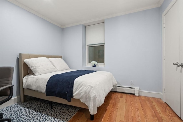 bedroom featuring light hardwood / wood-style floors, a baseboard heating unit, and crown molding