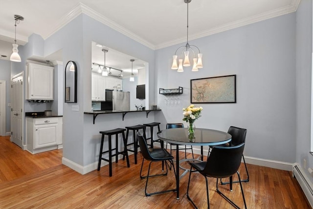 dining room featuring crown molding, baseboard heating, light wood-type flooring, and a notable chandelier