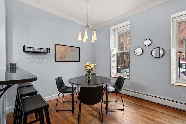 dining area featuring a notable chandelier, hardwood / wood-style flooring, ornamental molding, and a baseboard radiator