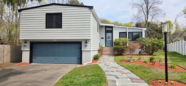 split level home with a garage, a front lawn, fence, and concrete driveway