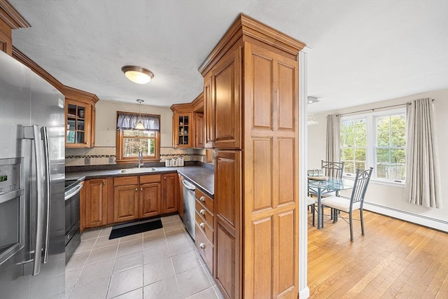 239 Upper County Rd, Dennis, MA 02660 - kitchen featuring stainless steel appliances, a sink, brown cabinetry, dark countertops, and healthy amount of natural light