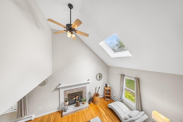 239 Upper County Rd, Dennis, MA 02660 - living room with baseboard heating, a skylight, a lit fireplace, wood finished floors, and a baseboard heating unit