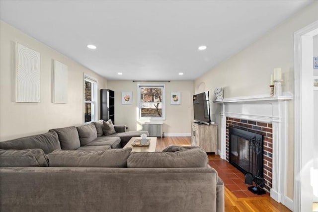 living room with radiator, baseboards, dark wood finished floors, recessed lighting, and a fireplace