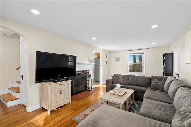 living area with stairway, recessed lighting, arched walkways, and light wood-type flooring