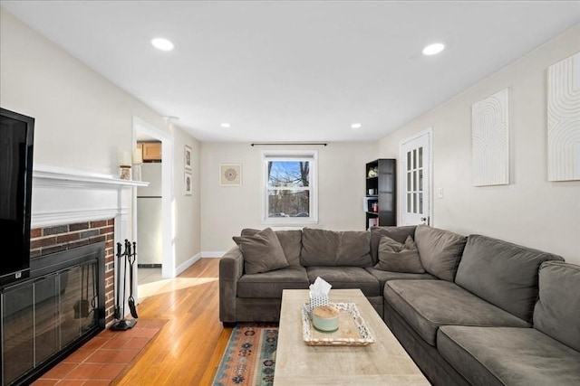 living room featuring a brick fireplace, recessed lighting, wood finished floors, and baseboards