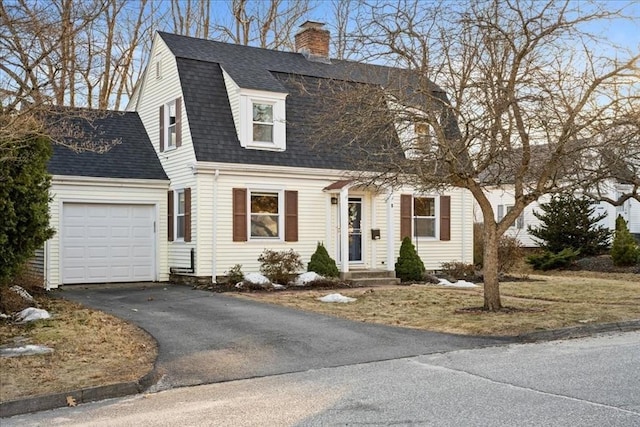 colonial inspired home with a chimney, a gambrel roof, driveway, and a shingled roof