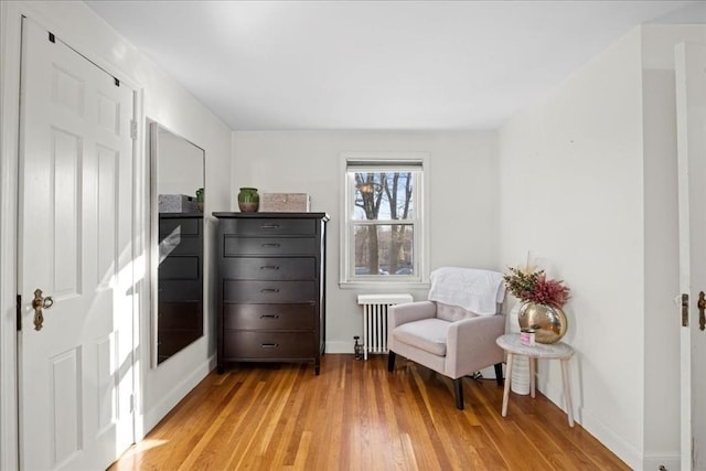 living area with radiator heating unit, baseboards, and light wood-type flooring