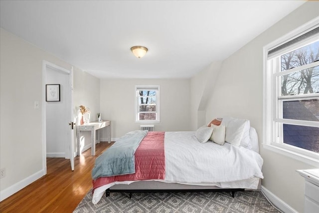 bedroom featuring radiator, wood finished floors, and baseboards