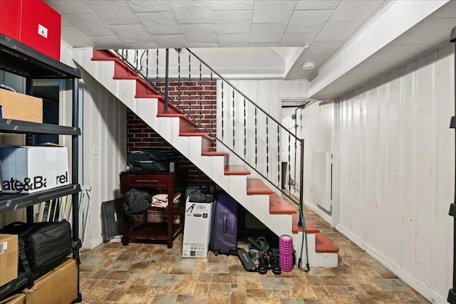 stairway with wooden walls and stone finish floor