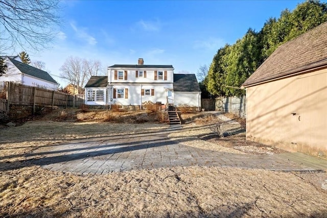 back of property featuring a chimney and fence