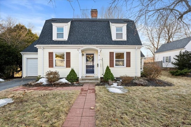 dutch colonial with aphalt driveway, an attached garage, a chimney, and a shingled roof