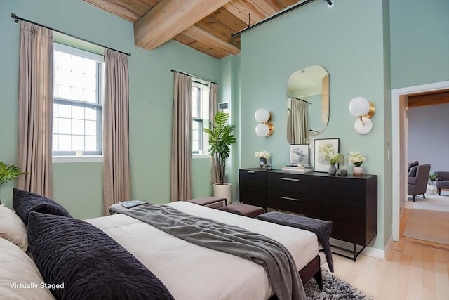 bedroom with beam ceiling, light wood finished floors, multiple windows, and wooden ceiling