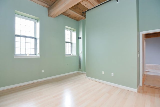 unfurnished bedroom with baseboards, wooden ceiling, beam ceiling, and wood finished floors
