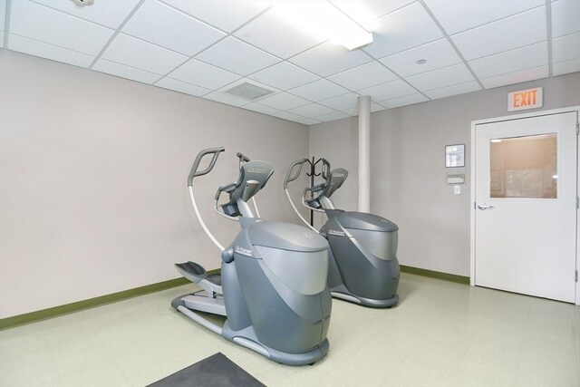 exercise area featuring baseboards, a paneled ceiling, and tile patterned floors