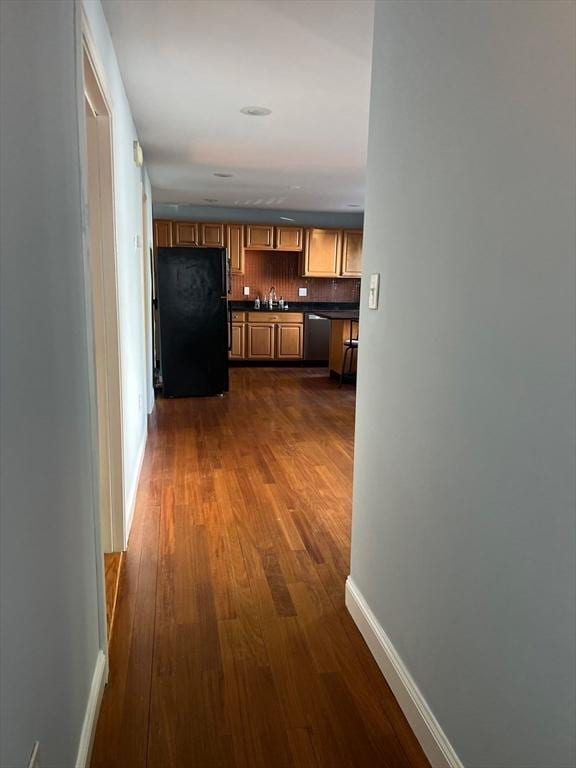 hallway with baseboards, dark wood-style flooring, and a sink