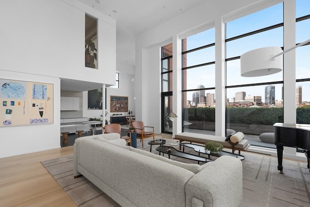 living room featuring light wood-type flooring and a towering ceiling