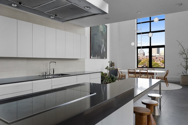 kitchen featuring backsplash, sink, exhaust hood, and white cabinetry