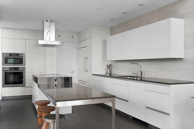 kitchen featuring appliances with stainless steel finishes, sink, island range hood, and white cabinetry