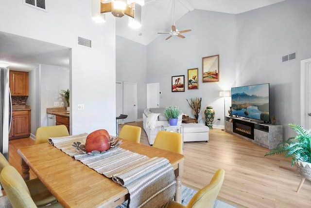 243 Trailside Way Unit 243, Ashland, MA 01721 - dining space with high vaulted ceiling, light wood-type flooring, ceiling fan, baseboards, and a glass covered fireplace