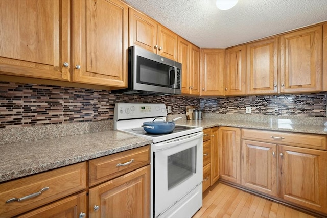 243 Trailside Way Unit 243, Ashland, MA 01721 - kitchen with electric stove, stainless steel microwave, light wood-style floors, tasteful backsplash, and a textured ceiling