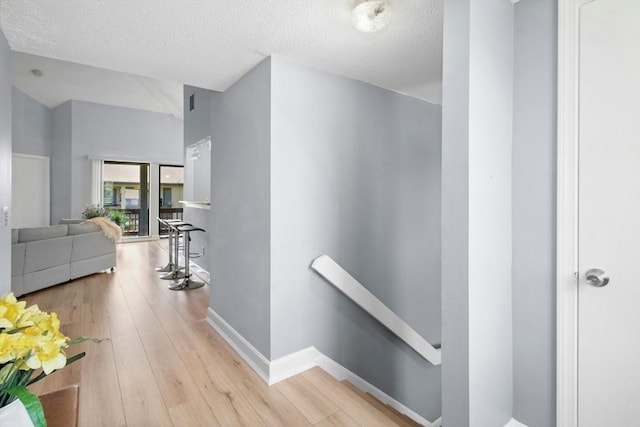 243 Trailside Way Unit 243, Ashland, MA 01721 - hallway with an upstairs landing, wood finished floors, a textured ceiling, baseboards, and lofted ceiling