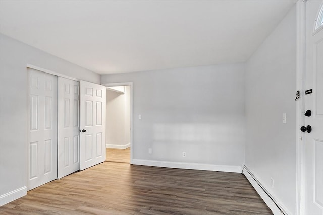 unfurnished bedroom featuring a closet, hardwood / wood-style flooring, and a baseboard radiator