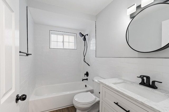 full bathroom with tile walls, toilet, vanity, and tiled shower / bath