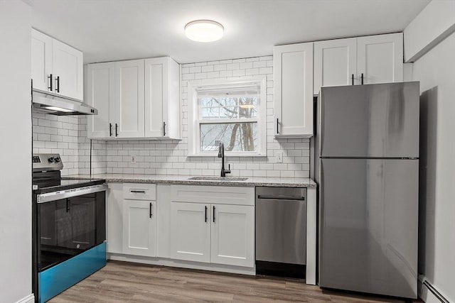 kitchen with sink, stainless steel appliances, white cabinets, baseboard heating, and light stone counters