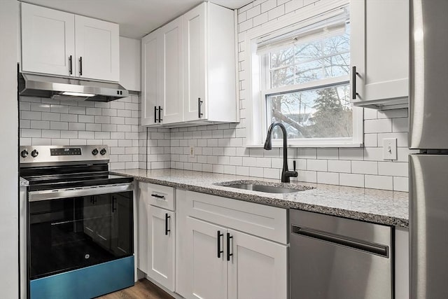 kitchen with light stone countertops, appliances with stainless steel finishes, white cabinetry, and sink