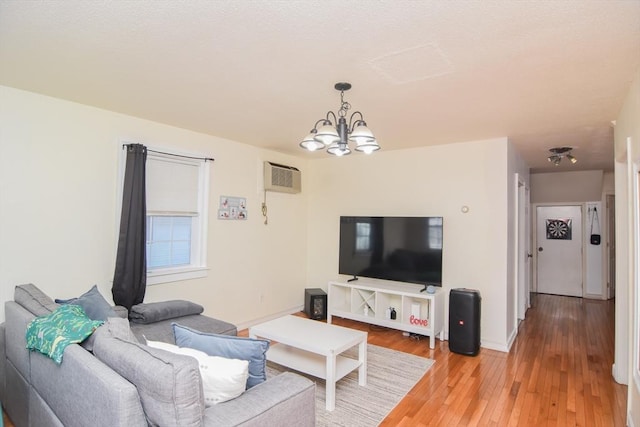 living area featuring baseboards, light wood-style flooring, an inviting chandelier, and a wall mounted AC