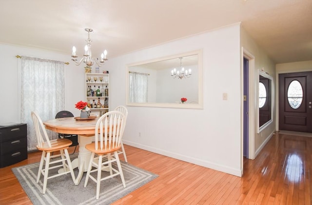 dining area with a chandelier, baseboards, and light wood finished floors