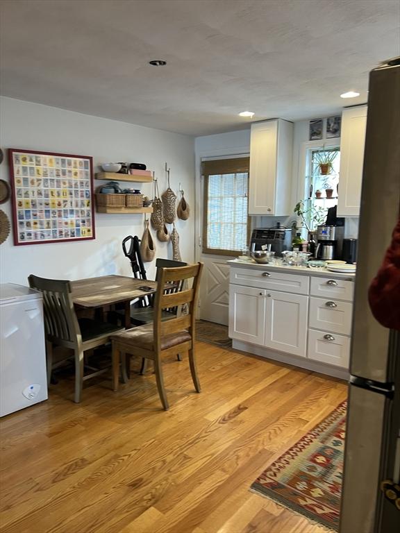 kitchen with stainless steel fridge, light hardwood / wood-style floors, and white cabinets