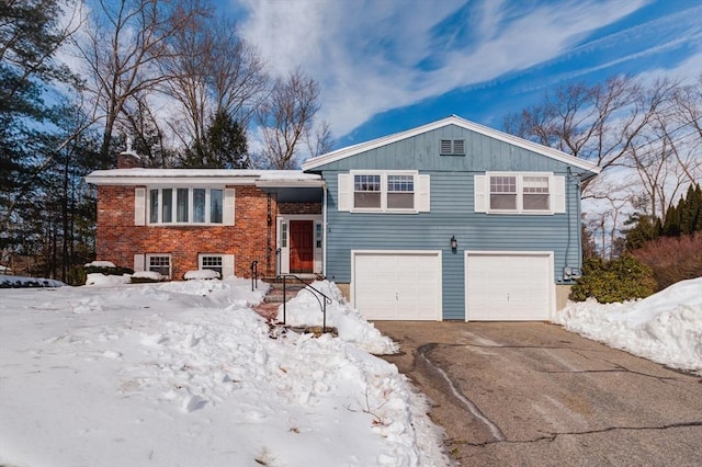 view of front facade with brick siding, driveway, a chimney, and an attached garage