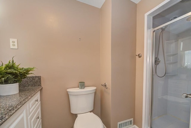 bathroom featuring toilet, vanity, a shower stall, and visible vents