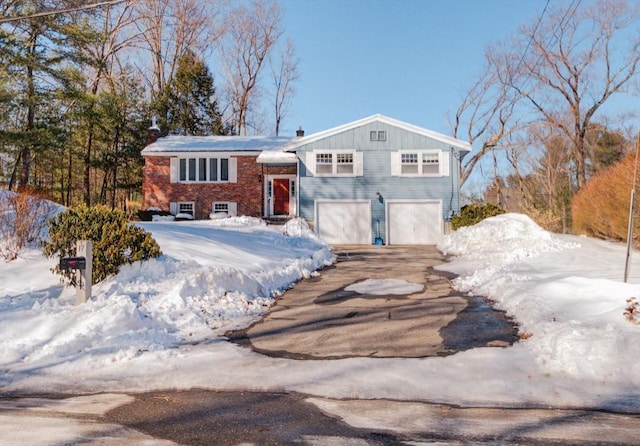 split foyer home featuring brick siding, driveway, and an attached garage