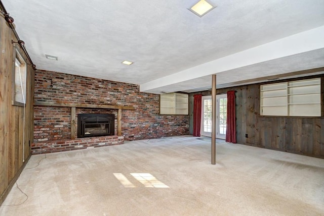 below grade area with a brick fireplace, light colored carpet, wood walls, and brick wall