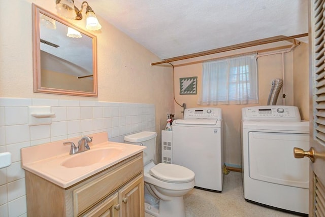 bathroom featuring separate washer and dryer, wainscoting, vanity, and tile walls