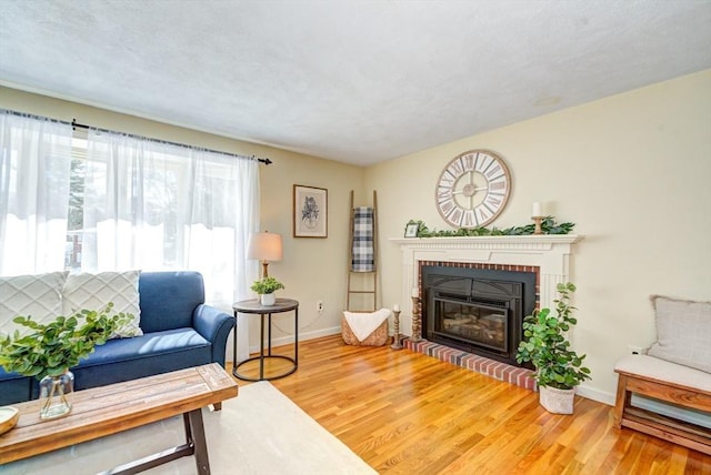 living room with a fireplace, baseboards, and wood finished floors