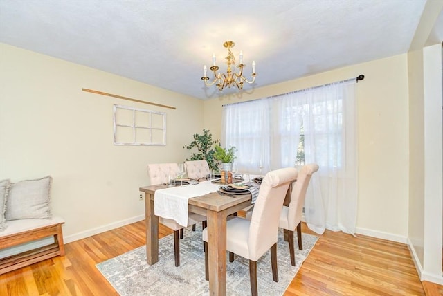 dining space with light wood finished floors, baseboards, and a notable chandelier