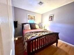 bedroom featuring wood finished floors, visible vents, and baseboards