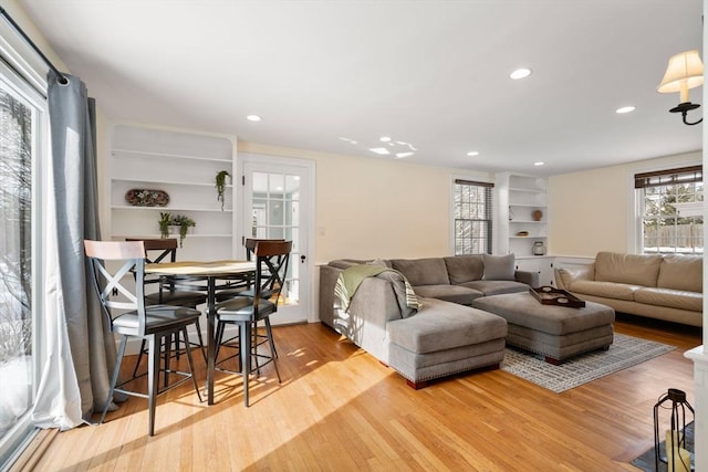 living room featuring built in shelves, plenty of natural light, and light wood-type flooring