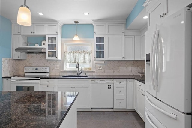 kitchen with tasteful backsplash, a sink, white cabinets, under cabinet range hood, and white appliances