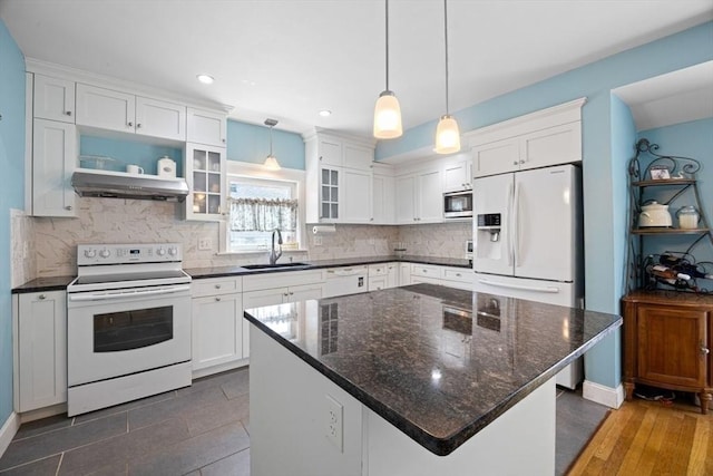 kitchen featuring a sink, under cabinet range hood, white cabinets, and white appliances