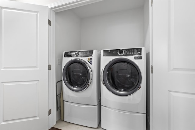 clothes washing area featuring separate washer and dryer and light tile patterned flooring