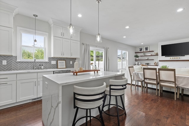 kitchen featuring light stone counters, sink, white cabinets, a kitchen island, and dark hardwood / wood-style flooring