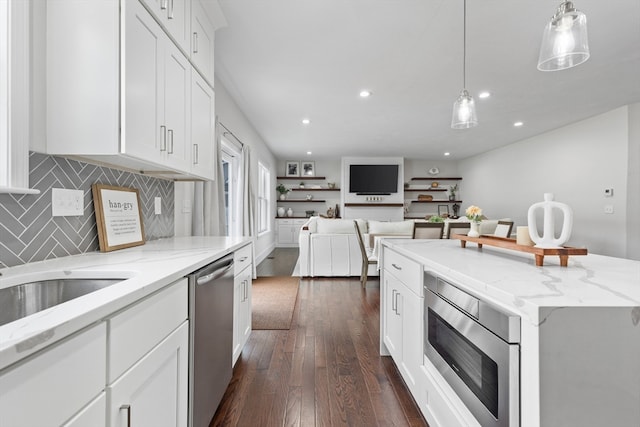 kitchen featuring appliances with stainless steel finishes, white cabinetry, a kitchen island, dark hardwood / wood-style flooring, and pendant lighting