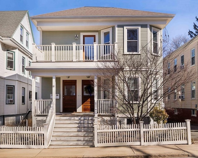 view of front facade with a porch, a fenced front yard, and a balcony